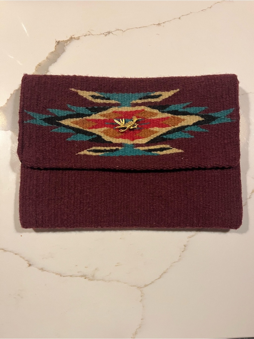 Woven burgundy and earth tone fold over clutch with antique gold tone pin